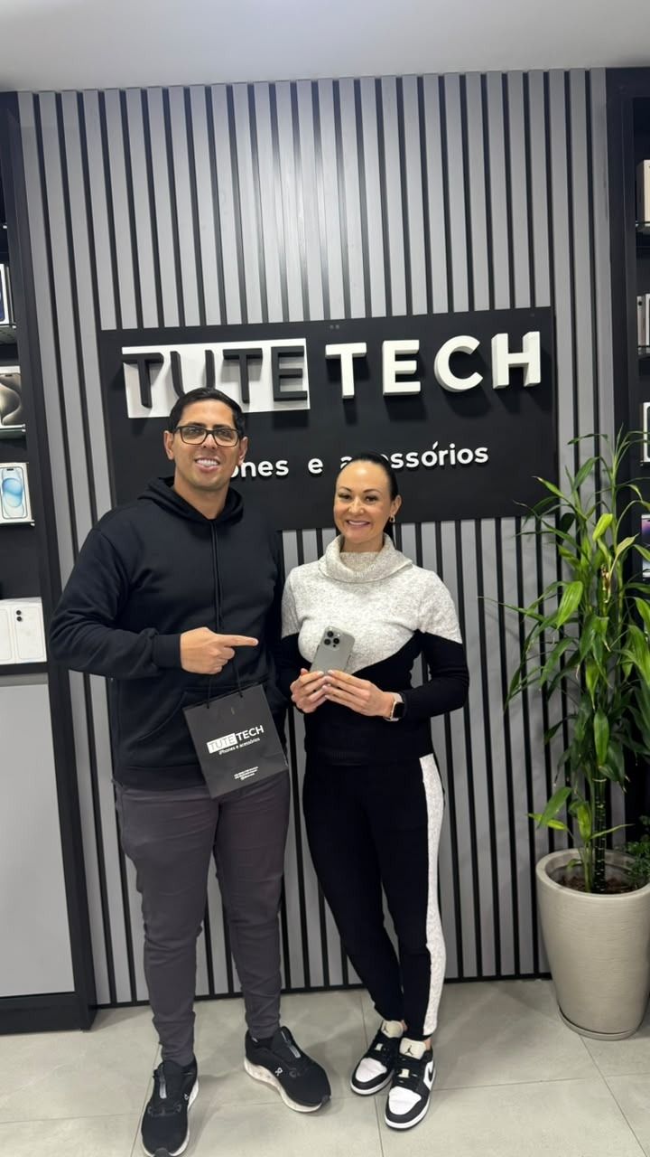 Consultor da Tute Tech ao lado de uma cliente que segura o iPhone novo