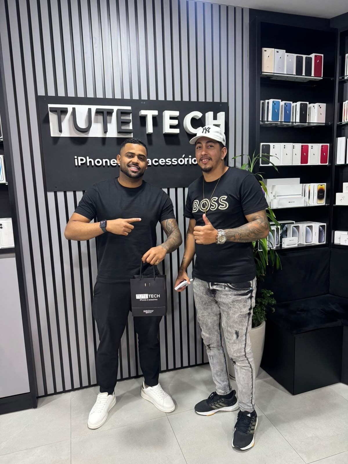 Cliente faz sinal de positivo ao lado do consultor, com as prateleiras da loja ao fundo