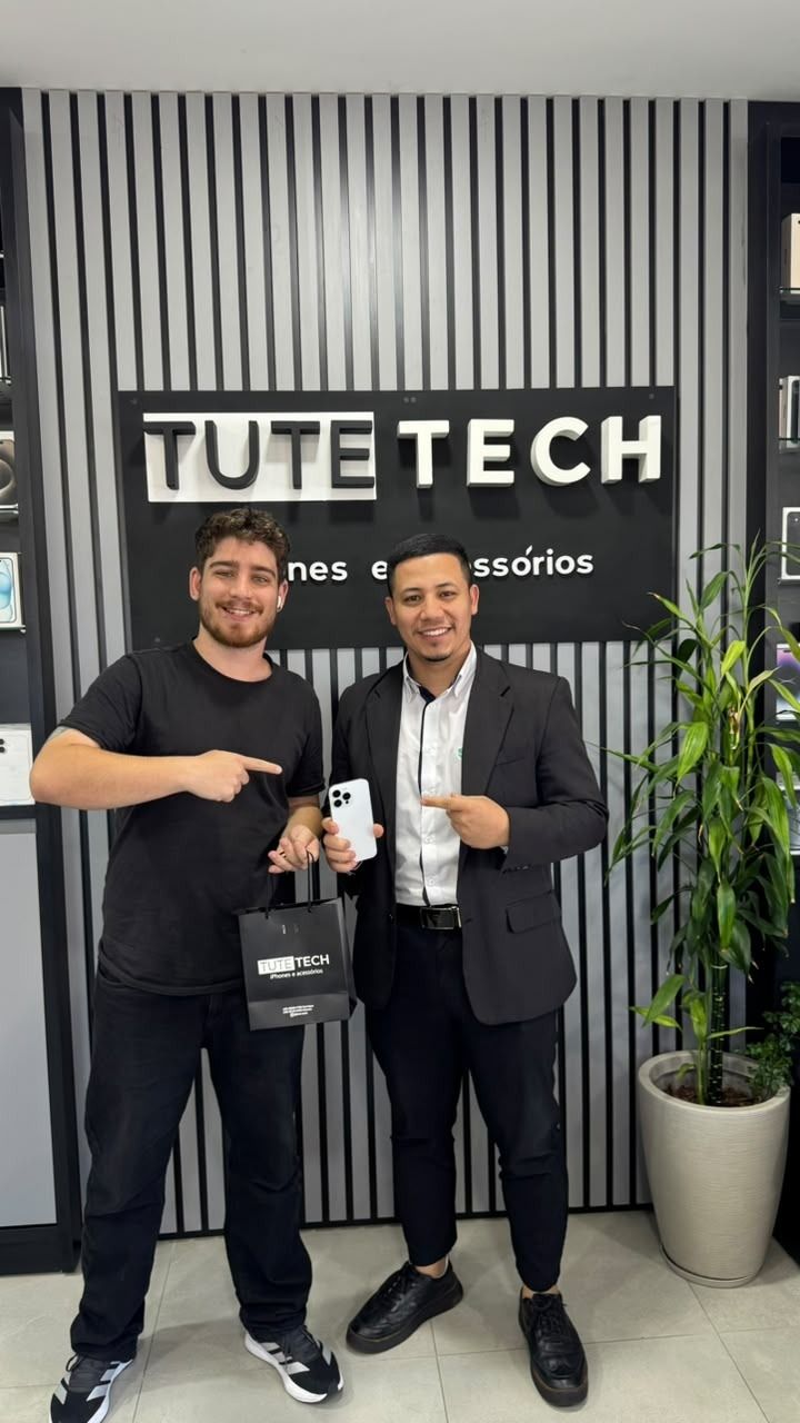 Cliente de terno com o iPhone novo, ao lado do consultor