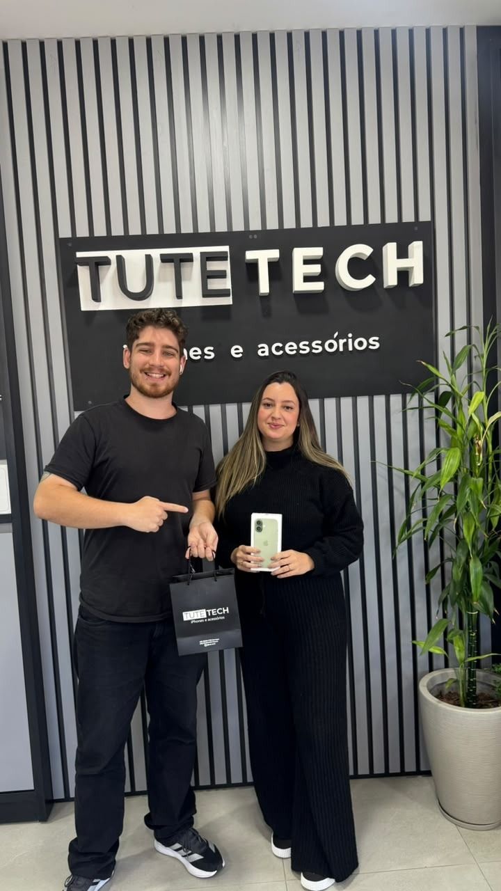 Cliente mostra o iPhone novo ao lado do consultor
