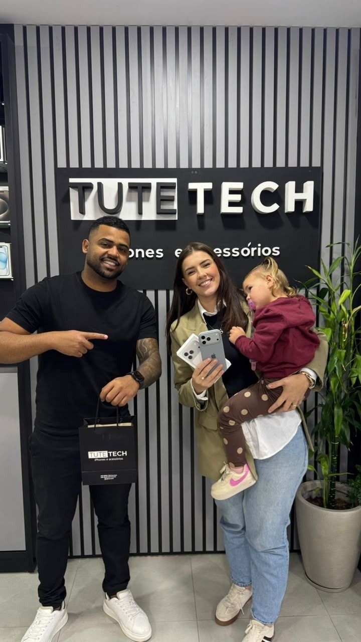 Cliente com a filha no colo mostra os iPhones novos ao lado do consultor