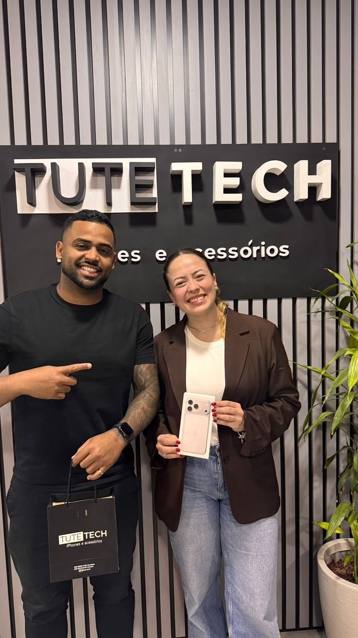 Cliente sorri com o iPhone novo, ao lado do consultor