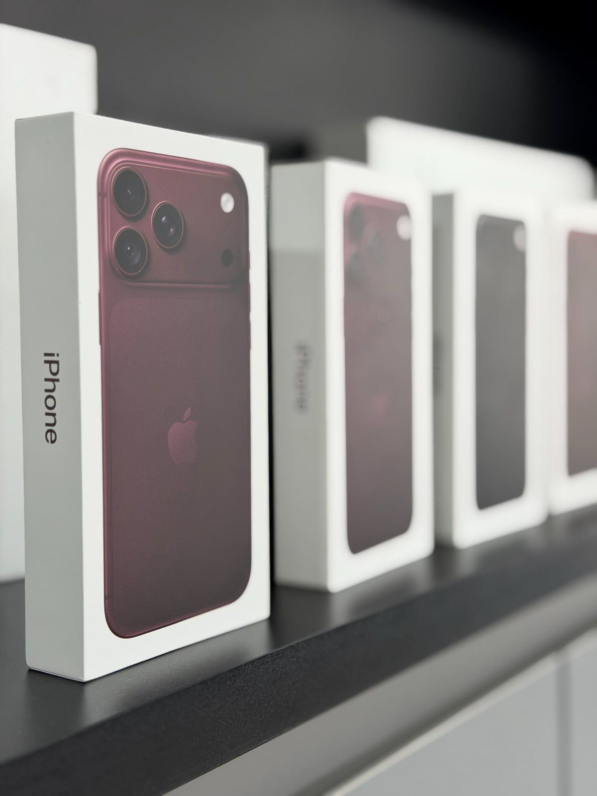 Caixas do iPhone 18 Pro na cor bordô, na vitrine da loja