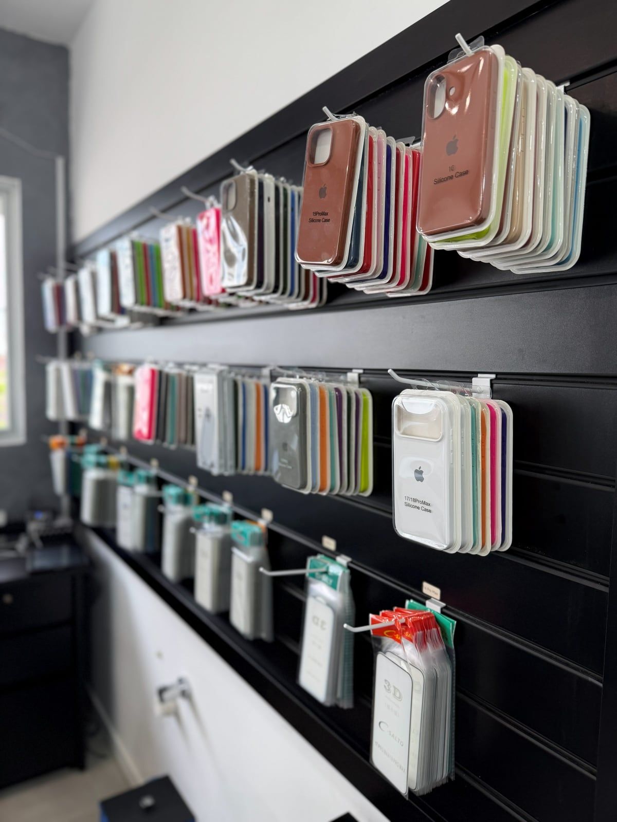 Parede da Tute Tech com capas de iPhone em várias cores