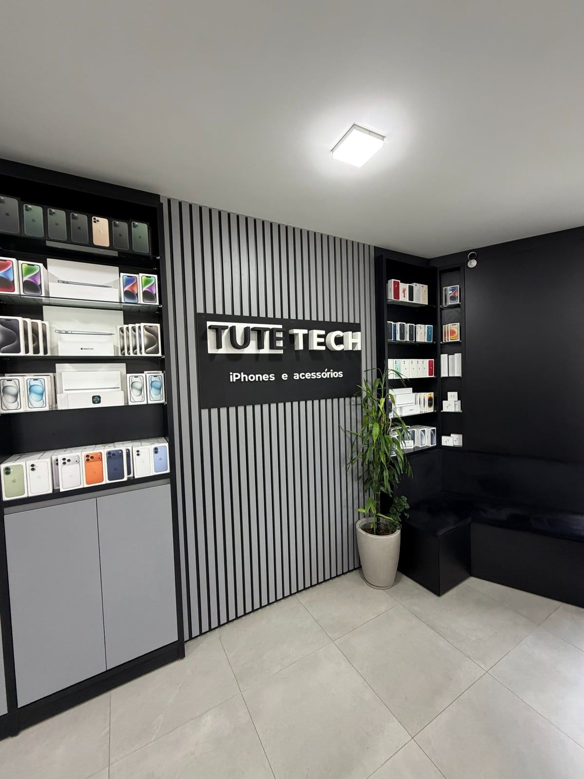 Interior da Tute Tech: vitrines com produtos e o painel ripado com o logo da loja